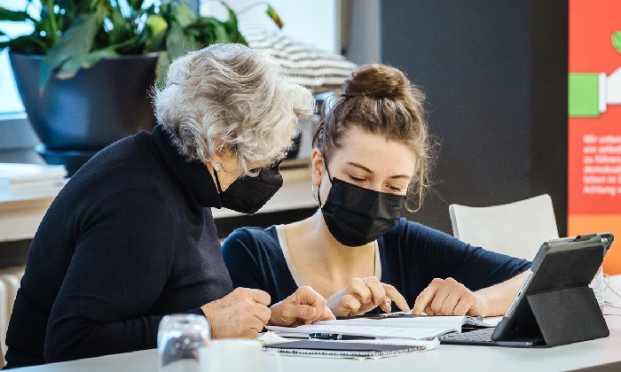 Eine Seniorin lässt sich von einer jungen Frau das Tablet und Smartphone erklären. Foto: AWO Köln